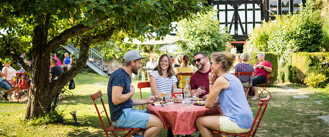 Freunde sitzen am Tisch und lassen sich den Moselwein schmecken